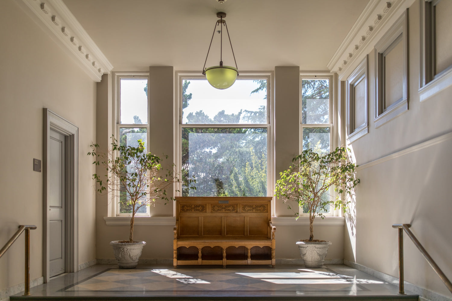 brown wooden bench kept between two white ceramic vase