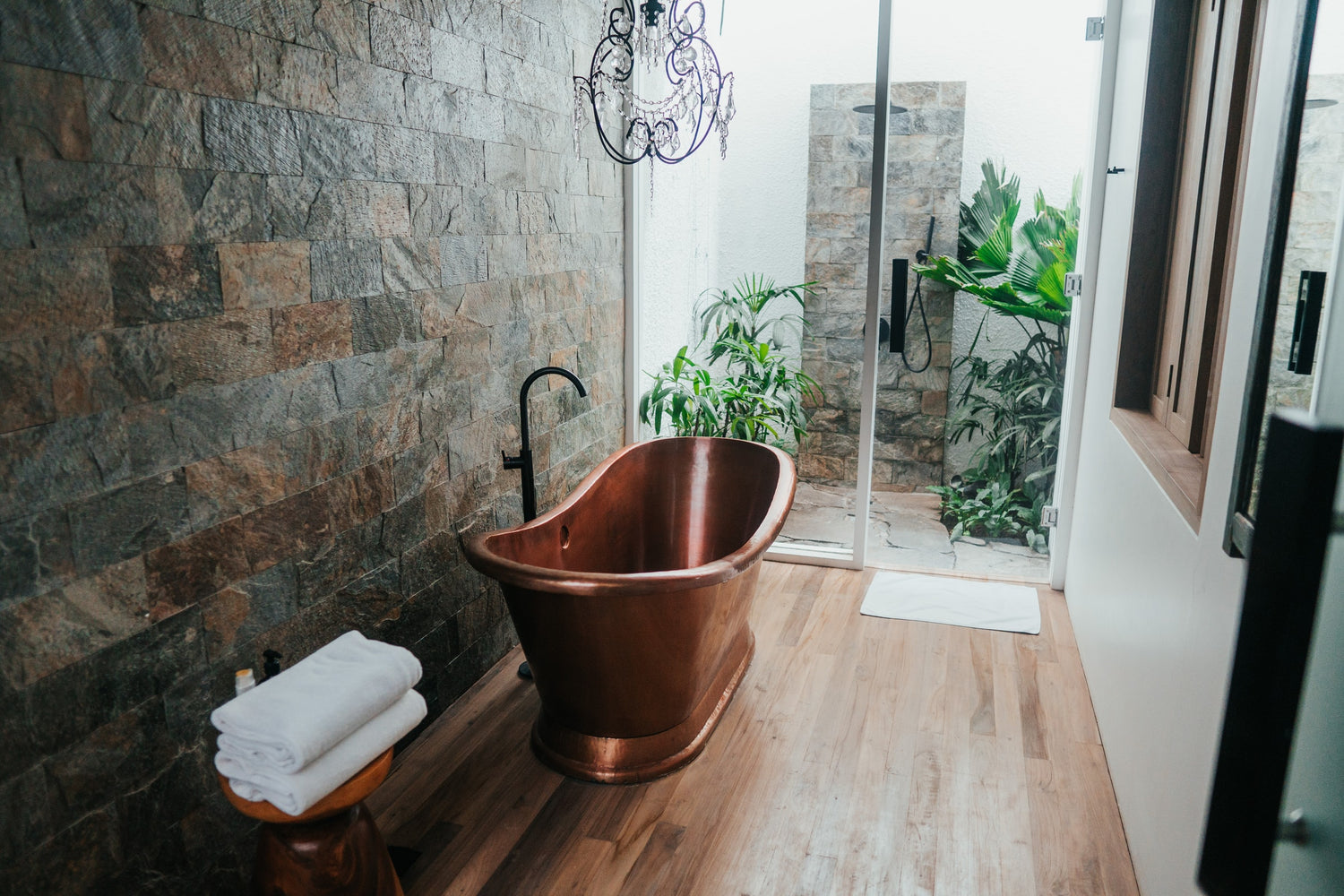 Copper bathtub placed on a wooden floor in bathroom