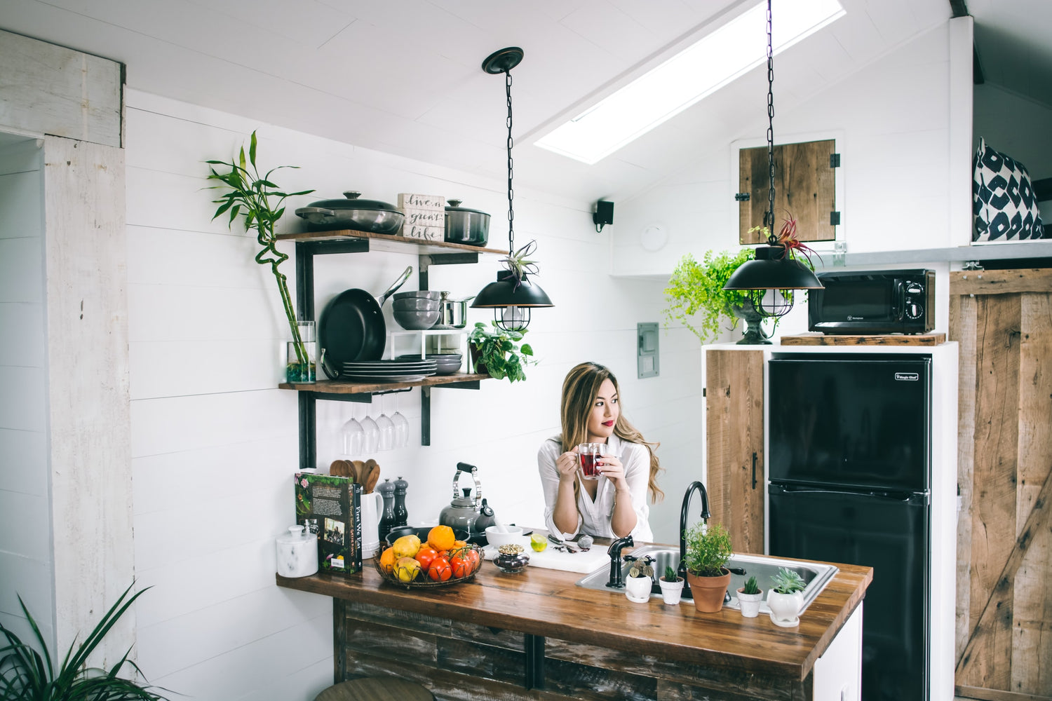woman in white tank top standing beside brown wooden table in kitchen